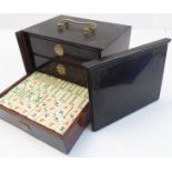 An early 20th century Mahjong set - bone-faced tiles and scoring chips within an Oriental three-