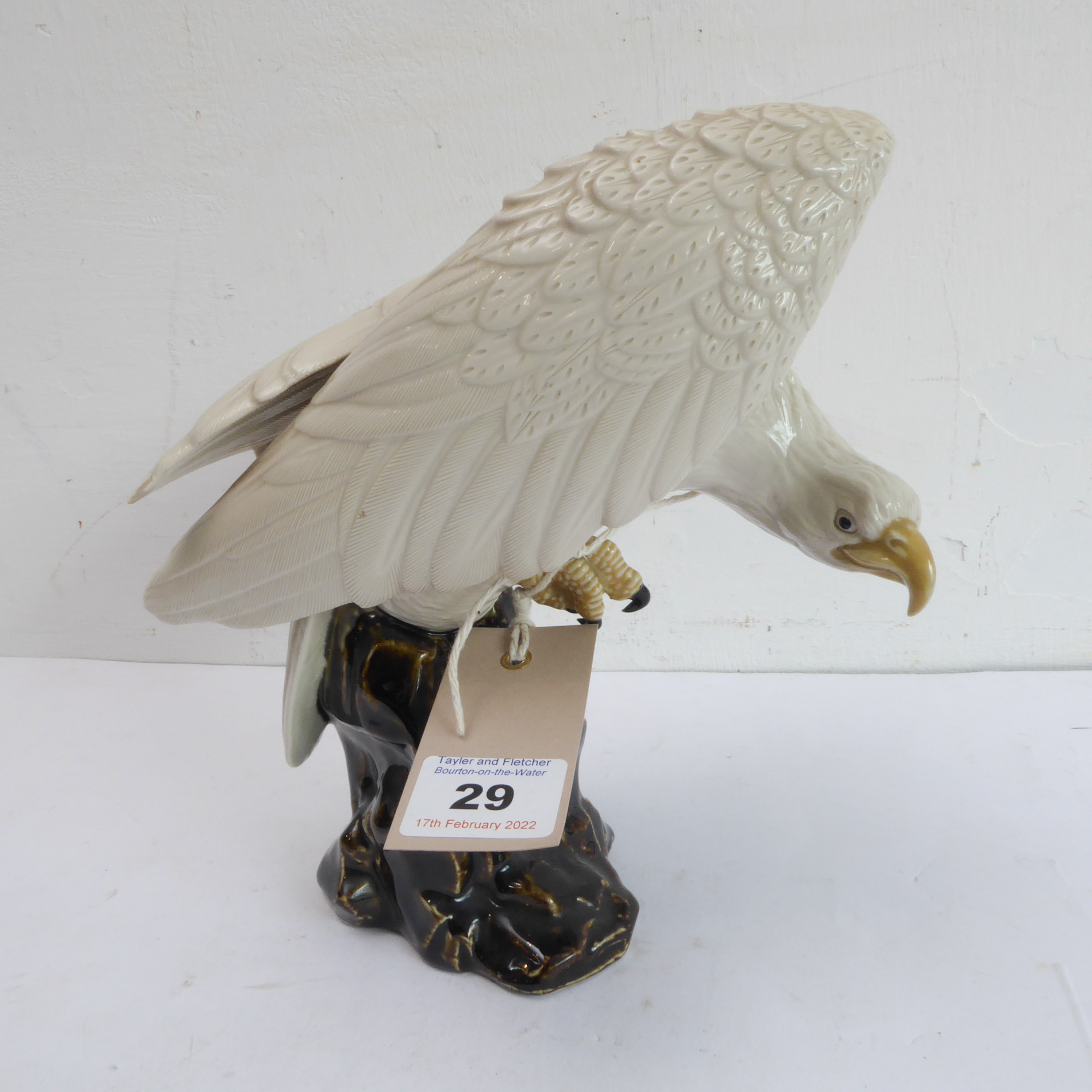 A 20th century hand-decorated porcelain model of a large white eagle perched upon rockwork (possibly