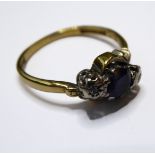 A sapphire and diamond-set ring, the circular-cut sapphire obliquely-set with a single-cut diamond