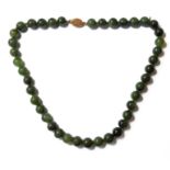 A green hardstone bead necklace (possibly green jade) - ornate filigree-style silver-gilt clasp (