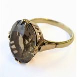 A yellow-gold ring (stamped 14K) centrally set with a hand-cut oval stone (probably smoky quartz) (