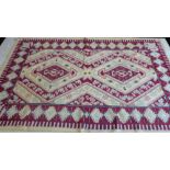 A handmade flat-weave rug - two central lozenges with red, yellow and pink borders and a claret