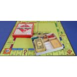 A mid-20th century Monopoly set with paper money, wooden houses and hotels, dice, cast-metal playing