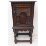 An early 20th century oak side cabinet in 17th century style: moulded top above arched panelled door