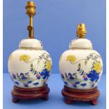 A pair of Chinese porcelain ginger jars and covers on wooden stands; hand-decorated in enamels