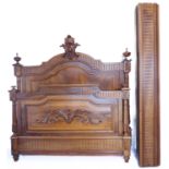 An early 20th century French walnut double bedstead: ornately carved baseboard and headboard, each