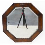 An Art Deco period octagonal oak framed wall hanging looking glass having hand bevelled plate