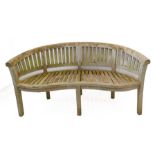 A weathered teak 'banana bench'; slatted back and raised on six square legs (160cm wide x 85cm