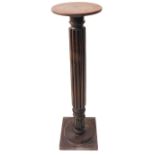 A circular oak-topped torchère stand; reeded stem above a lotus-style bulb on square shallow