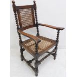 An imposing 1920s /1930s stained wood and rattan caned open armchair; barley-twist supports and high