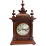 A late 19th century walnut eight-day mantle clock; the pediment finials above a silvered dial with