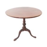 A George III period circular mahogany tilt-top occasional table; one-piece top, turned stem and
