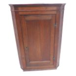 A late 18th century hanging oak corner cupboard; single panelled door opening to reveal painted,