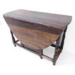 An early/mid 18th century oval oak drop-leaf gateleg table; baluster-turned supports united by