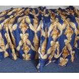 A pair of blue and gold lined curtains in a striking pattern of ribbons and tassels, pencil pleat