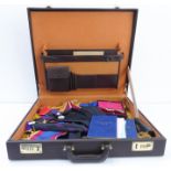 A brown case containing a wide variety of Masonic regalia to include various jewels, apron, ties,