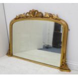A 19th century carved giltwood overmantle mirror; the pierced foliate cresting above an arched plate