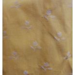 A pair of yellow curtains with woven small floral pattern, edged with corded and fringed braid,
