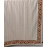 A pair of curtains in a heavy cream woven striped fabric edged with a red and cream patterned border