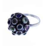 An unusual silver dress ring of domed design mounted with various coloured stones/glass polished