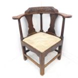 A mid-18th century heavy oak corner chair - the carved concave back-rest above gun-barrel-style