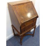 An early 20th century walnut veneered writing bureau of small proportions: the banded fall above two