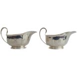 A pair of heavy hallmarked silver sauceboats: high arched reeded handle and on slightly spreading