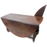 A large oval topped 18th century oak drop-leaf gateleg table: the two drop-leaves supported on