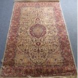 2 An all wool Kashmiri carpet; teardrop medallion against an ivory ground with a claret-red main