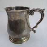 A George II period hallmarked silver tankard of baluster form with leaf-capped handle and on