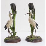 A pair of cold-painted bronze candlesticks modelled as opposing storks in front of large