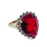 A lady's dress ring centrally set with a hand-cut pear-shaped deep-red stone surrounded by a smaller