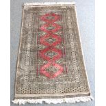 A modern Pakistan rug; rose ground with multiple borders (signed to one end) (167cm x 93.5cm)