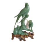 A Chinese green hardstone carving of an elaborate crested bird upon a branch with one other