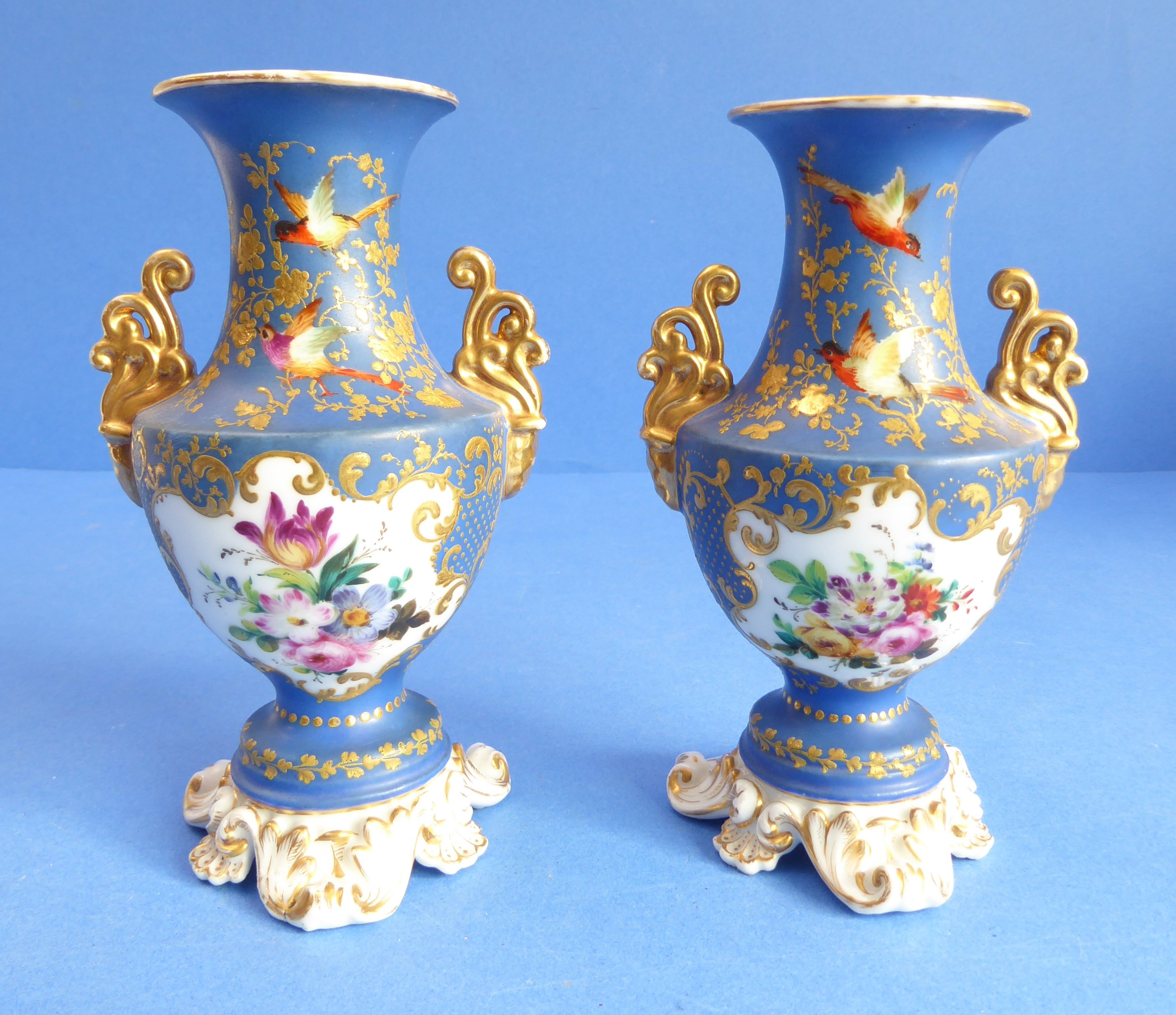 A pair of 19th century French porcelain vases: each with two gilt handles and vignettes of floral