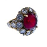 A large and showy bespoke custom-made ring, the large deep-red circular hand-cut stone surrounded by