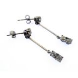 A pair of 18 carat white gold diamond dropper earrings, each set with three old cut diamonds (