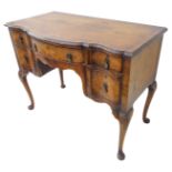 An early / mid 20th century figured walnut veneered serpentine-fronted dressing table: the quarter