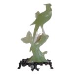 A large and elaborate Chinese light-green hardstone carving of a crested bird perched upon a gnarled