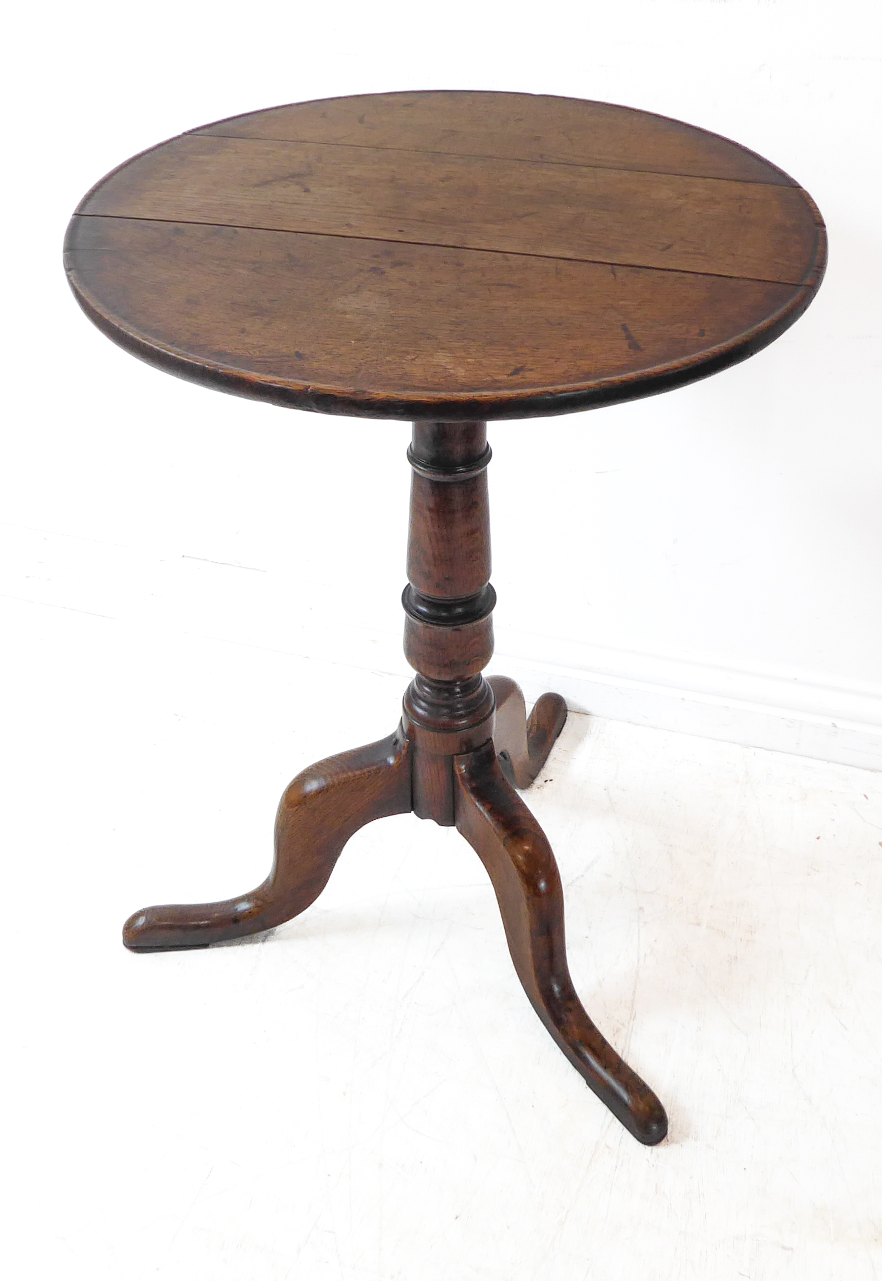 A George III period 18th century circular topped oak occasional table, tuned stem and on tripod base