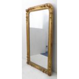 A large 19th century gilt-framed looking glass; the cushion-moulded frame modelled in high relief