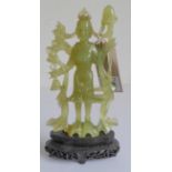 A Chinese carved light-green hardstone carving of a standing female figure, a staff in her left hand