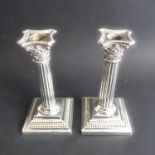 A pair of sterling silver table candlesticks modelled as Corinthian columns with acanthus