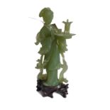 A carved Chinese light-green hardstone standing female figure, in her left hand she holds an oval