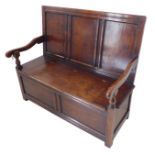 A good 18th century style (later) reproduction solid oak panel back settle: hinged top over two