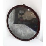 A late 18th/early 19th century circular mahogany-framed wall-hanging looking glass with original