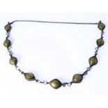 An unusual Eastern style silver necklace, nine bulbous lozenge shapes each engraved with stylised