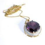A circular silver-gilt pendant centrally set with a hand-cut amethyst-coloured stone surrounded by a