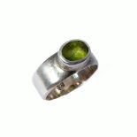 A silver ring set with a hand-cut horizontal oval stone (probably a peridot), ring size R