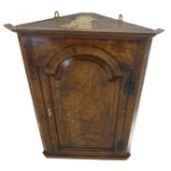 A mid 18th century style (good later reproduction) hanging oak corner cupboard: single arch-topped